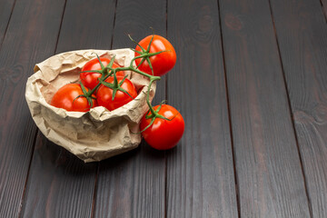 Juicy red tomatoes on green branch and wrapped in brown paper.