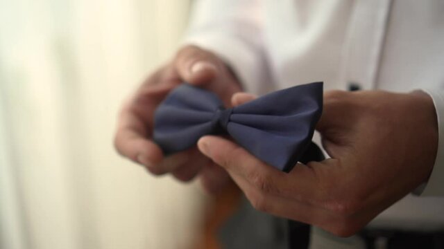 a man holds a bow tie in his hands