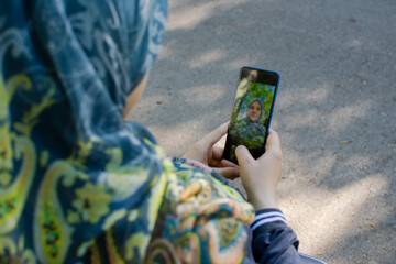 Muslim pregnant woman taking selfie in the park