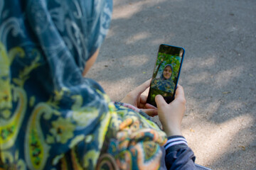 Muslim pregnant woman taking selfie in the park