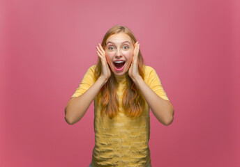 Overjoyed excited young girl surprised by win enjoy victory rejoice success screaming wow on pink studio background
