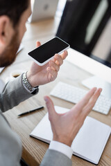 Blurred businessman recording voice message on cellphone in office.