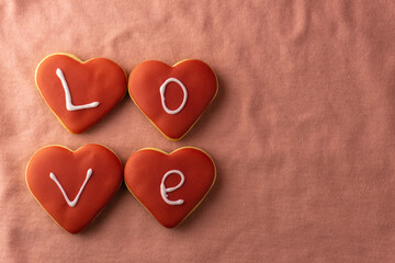 Gingerbread cookies with the inscription love on a pink background. Valentine's day concept. Heart-shaped gingerbread. Copy space.