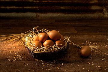 A basket of fresh brown eggs on a textured wooden floor against a textured corrugated iron wall...