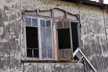 Broken casement windows on an old abandoned old farm house in North Queensland, Australia, with asbestos fibre cement walls now derelict .