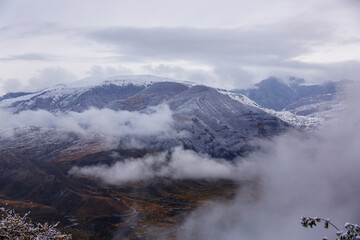 Panoramic view from the Gunib village, Dagestan, Russia. Snow-capped mountains and autumn fields. Beautiful mountain landscape in winter. Foggy forest hills