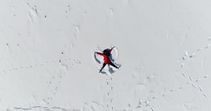 happy woman lies in the snow and makes an angel