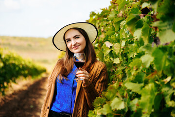 Attractive winemaker woman holding a glass of red wine in her hand and looking at the camera....