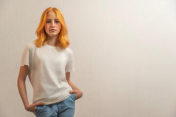 teenage girl with red hair in a white T-shirt on a blonde background © Olleg1