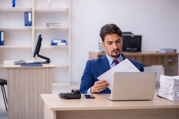 Young businessman employee and too much work in the office