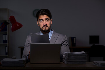 Young male employee working late in the office