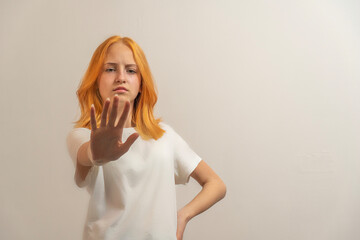 teen girl with red hair in a white t-shirt on a light background denial to say no - obrazy, fototapety, plakaty