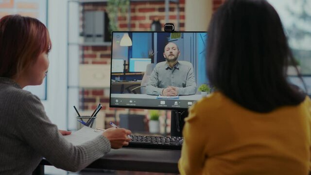 Business women attending online job interview on video call, using computer to talk to candidate about employment. Coworkers interviewing applicant about hiring contract on remote teleconference.