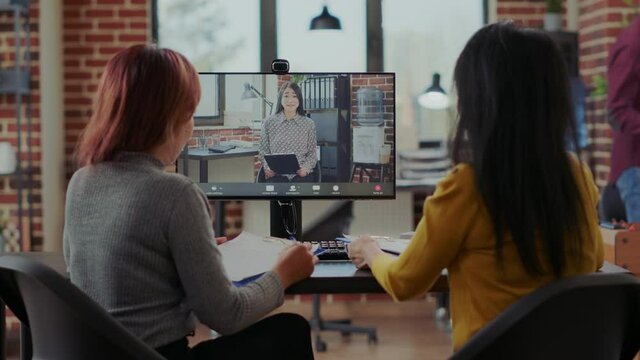 Asian women interviewing candidate to fill job vacancy on video call in startup office. Company workers meeting with woman to hire intern on contract, using online videoconference on computer.