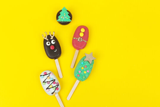 Set of different Christmas cookies donats and cakesicles on yellow background