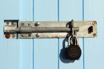Old light blue painted wooden door planks with metal padlock