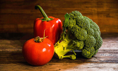 Broccoli, tomato, bell pepper on a wooden oak table.