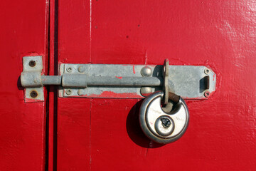 Old red painted wooden door planks with metal padlock