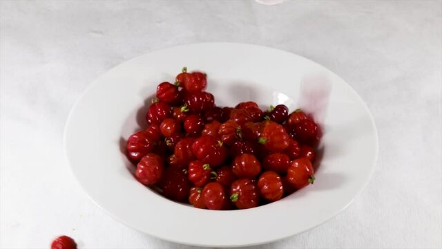 Ripe pitangas (Eugenia uniflora), falling on the white plate