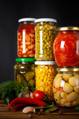 Jars of various pickled vegetables on a dark background. Canned food