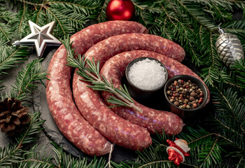 christmas raw  sausages with spruce and christmas toys on stone background 