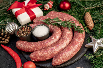 christmas raw  sausages with spruce and christmas toys on stone background
