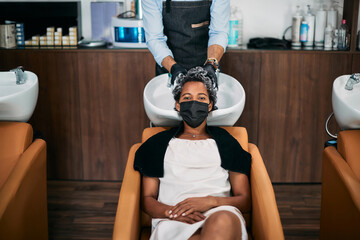 African American woman getting hair wash at hairdresser's during coronavirus pandemic.