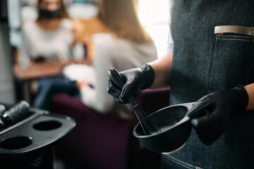 Close-up of hairdresser mixing dye in a container at hair salon.