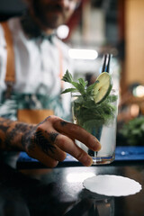 Close-up of barman serving mojito cocktail at bar counter.