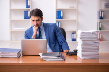 Fototapeta premium Young businessman employee and too much work in the office