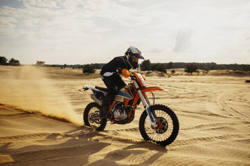 Obraz na płótnie Canvas Professional motocross rider driving on sand dune