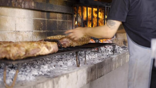 Chef colocando carne a la parrilla. Cocinando sobre fuegos el t&iacute;pico asado argentino.
