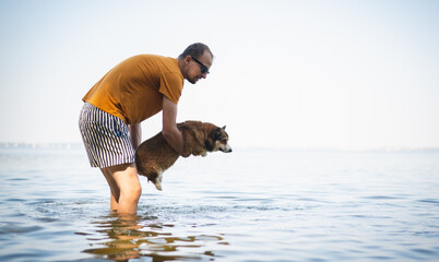 A man teaching a corgi dog how to swim