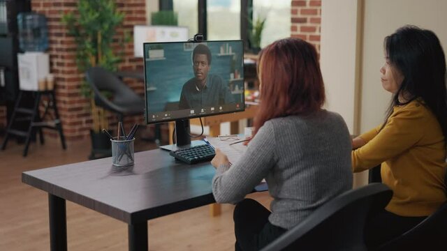 Coworkers using video call on computer to talk to candidate at job interview. Asian women attending remote meeting with applicant on video teleconference to discuss hiring and intern contract.