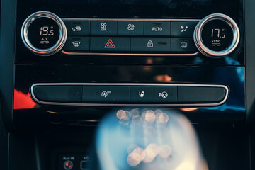 Digital climate control knob in a car in dark color. Gear change knob out of focus. Car interior.