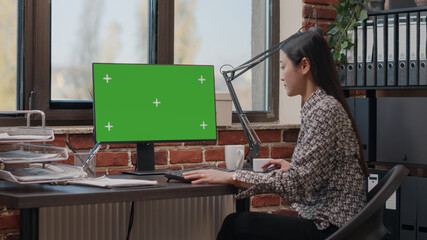 Person using computer with green screen in business office. Woman looking at isolated mockup...