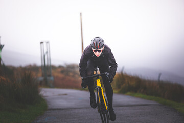 Obraz premium Young caucasian man sprinting on a road bike at the top of the mountain.