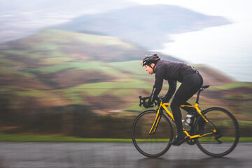 Pan shot of a young caucasian cyclist man sprinting on his bike.