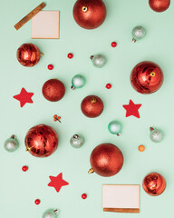 Red and green Christmas baubles with star decoration on pastel green background.  Retro wooden copy...