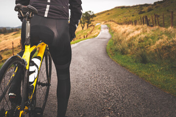 Unrecognizable cyclist standing on his bike on an asphalt road.