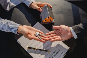 Real estate agent is handing over the house and keys to the customer after the contract is signed. Concept of mortgage, lease, purchase and home insurance.