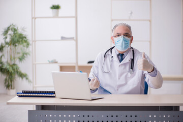 Old male doctor working in the clinic