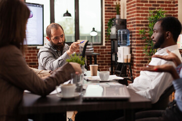 Diverse businesspeople discussing management strategy planning company presentation during business meeting in startup office. Entrepreneurs working brainstorming ideas for partnership