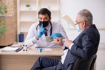 Obraz premium Old businessman visiting young male doctor in vaccination concep