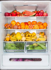 close up of full open fridge with fruits and vegetables. healthy food background.