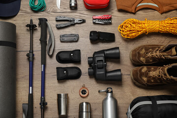 Flat lay composition with trekking poles and other hiking equipment on wooden background