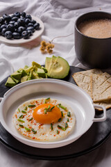 Healthy homemade breakfast with chocolate, fried egg with chives, toast, avocado and blueberries.