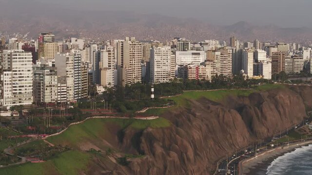Panoramic  aerial view of Lima city, with deail of the cliff, the green coast and the poor towns of the hills  at the background.