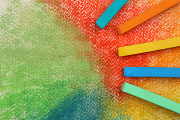 Colorful pastel chalks on abstract drawing, flat lay. Space for text