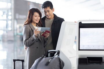 Happy young couple doing self check-in at the airport